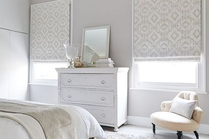 cream roman blinds in a bedroom with 2 windows 
