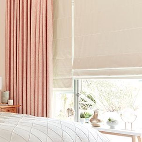 pink curtains with cream roller blinds in a bedroom window 