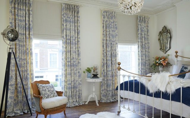 Blue and white curtains paired with white striped roman blinds in a bedroom decorated in white and blue