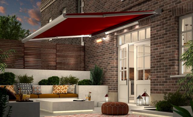 Garden Awning in Verona Rouge fabric extended over garden patio in the evening