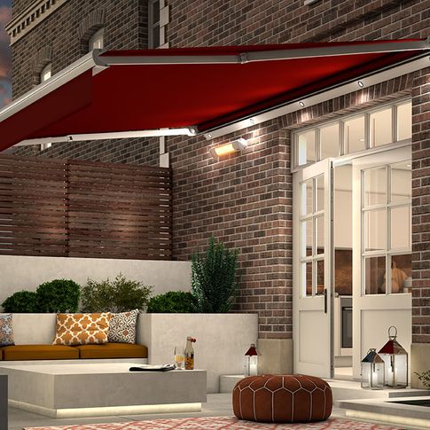 Garden Awning in Verona Rouge fabric extended over garden patio in the evening