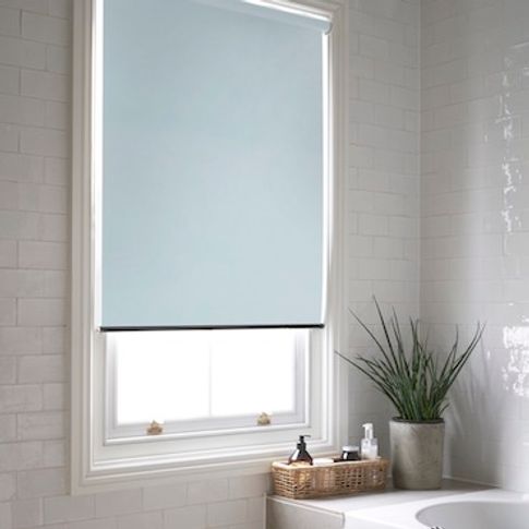 Acacia Azure roller blind on a window in a white tiled bathroom