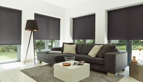 Plain black roller blinds hung in living room