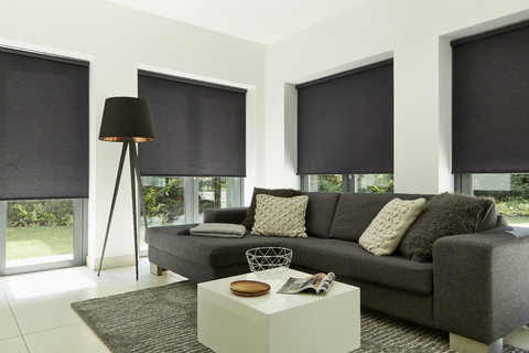 Plain black roller blinds hung in living room