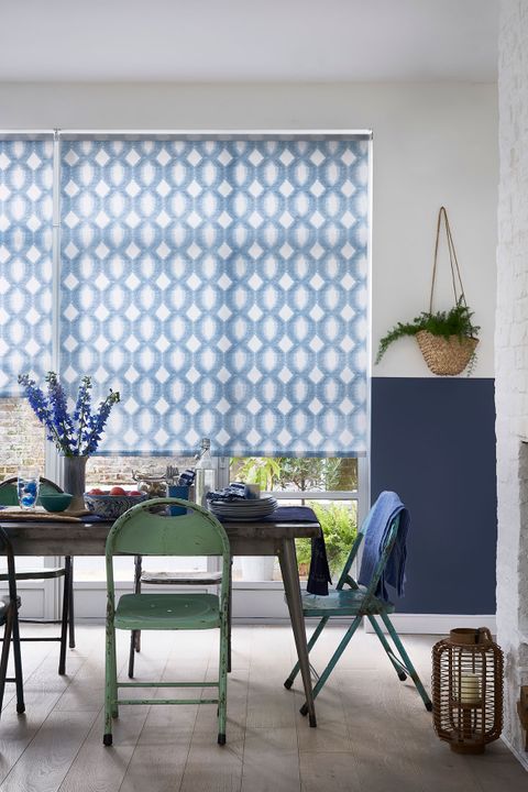 Patterned blue roller blind hung across a wide patio door window in a dining room