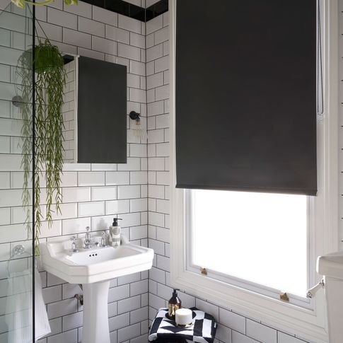 Black roller blind hung in bathroom with monochrome decor