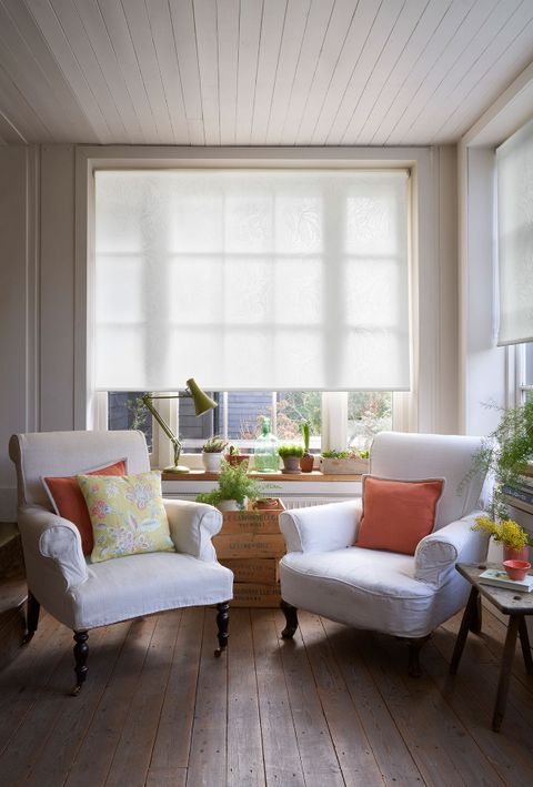 Living room with two white armchairs and white roller blinds