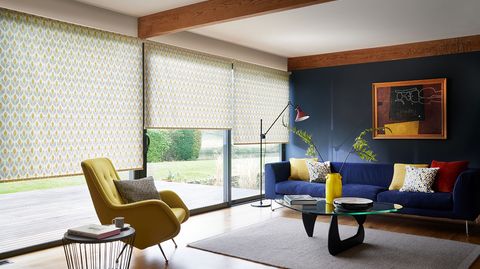Modern living room with retro style decor and wide windows dressed with retro yellow floral roller blinds