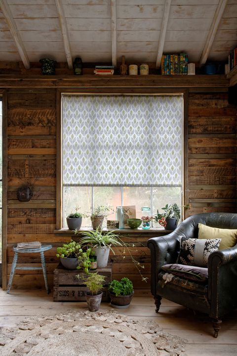 Rustic living room with wood panel walls and window dressed with green retro roller blinds