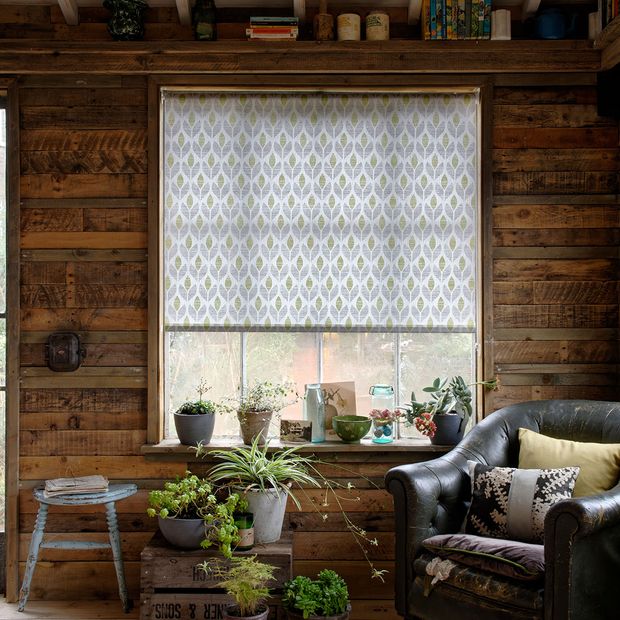 Rustic living room with wood panel walls and window dressed with green retro roller blinds