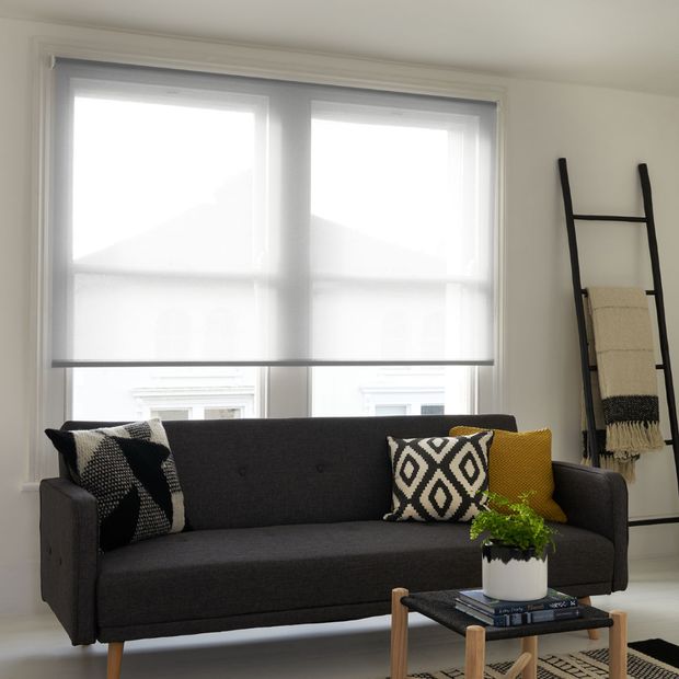 Modern minimalist living room with dark grey sofa and window dressed with voile roller blinds 