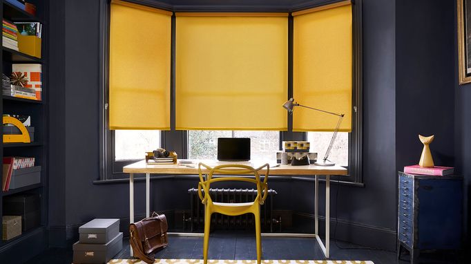 Home office with dark walls and colourful mustard roller blinds