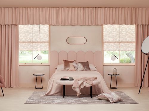 A pink bedroom with pink soft furnishings 