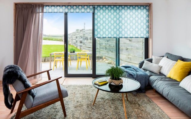 charlie luxton's living room with blue patterned roller blinds in a patio window 