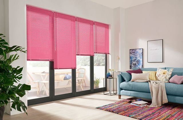 Close up of a pink Venetian blind across bi-fold doors in a living room