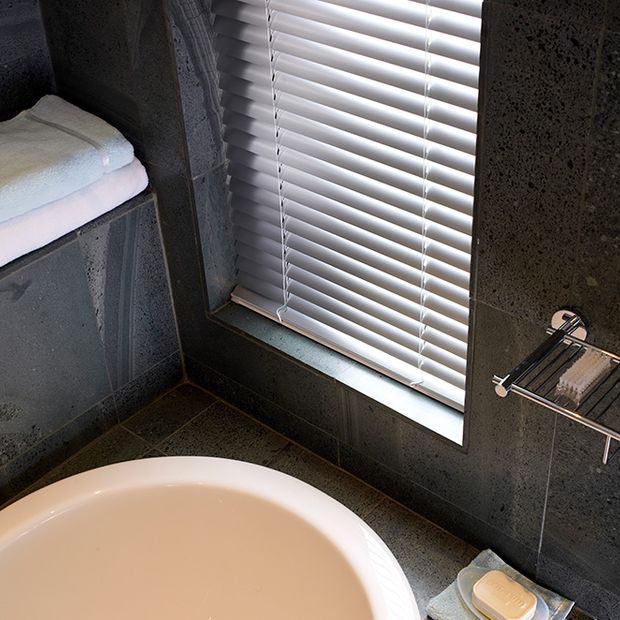 A close up of silver Venetian blinds in a bathroom