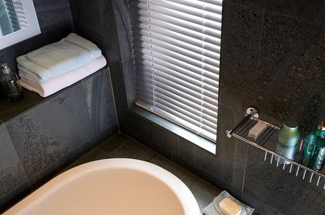 A close up of silver Venetian blinds in a bathroom