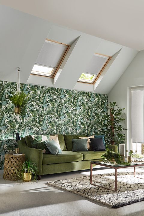 Skylight blinds in Acacia Silver are fitted to two skylight windows in a living room decorated in floral colours including the wallpaper, sofa and various plants