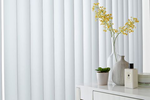 A close up of white vertical blinds in a window