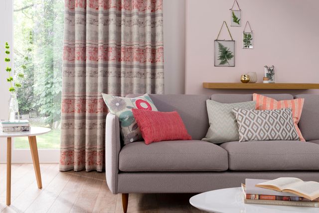 Coral and white coloured curtains attached to a door window in a living room decorated with pink walls