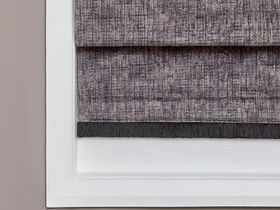 Light grey coloured roman blind with dark grey highlights fitted to a rectangular shaped window in a room with beige coloured walls