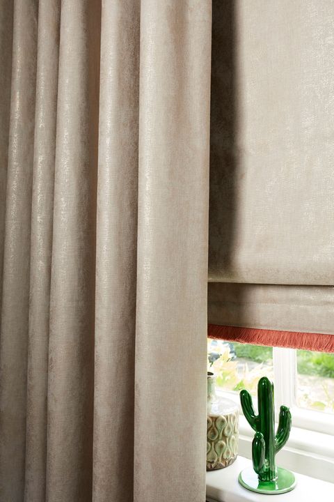 Cream roller blinds paired with cream curtains fitted to a rectangular shaped window