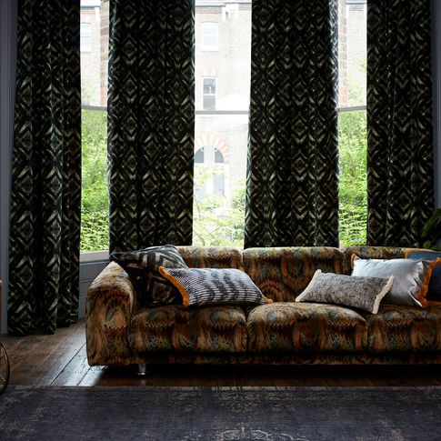 Edgy living room with dark decor and black and green velvet curtains from the Abigail Ahern collection