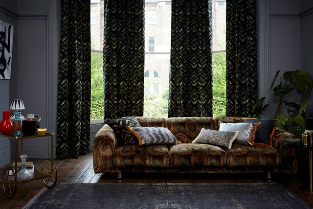 Edgy living room with dark decor and black and green velvet curtains from the Abigail Ahern collection