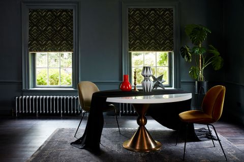 Modern gothic dining room with dark green patterned roman blinds by Abigail Ahern