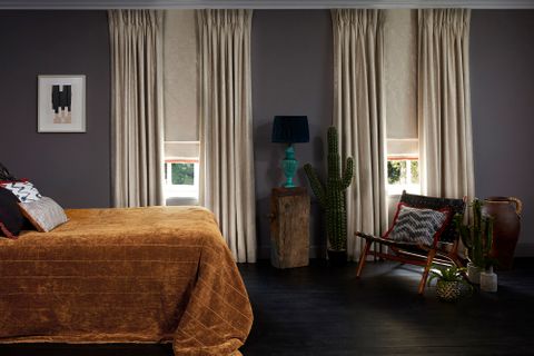 Bedroom with edgy decor and neutral Curtains in Abigail Ahern Lucien Dust fabric layered with Lucien Dust Roman Blind with a Colette Amour Orange Fringing