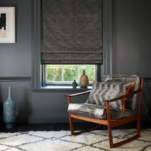 Dark living room with retro armchair and grey roman blinds