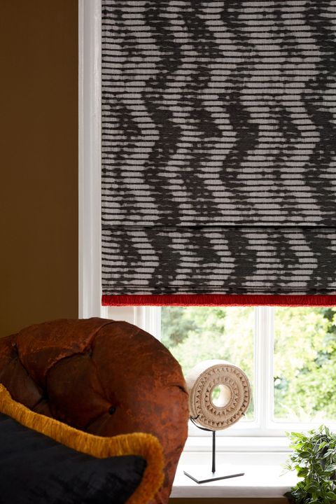 Close up of pattern roman blinds with red contrast fringing