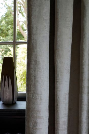 Close up detail of grey textured velvet curtains and black and white vase