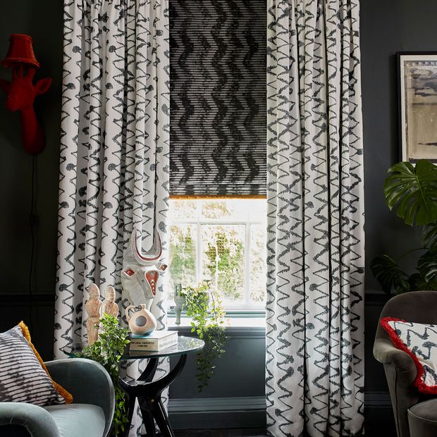 Dark and Eccentric Living Room decorated with White pattern curtains in Wolfe Smoulder fabric layered with a dark pattern roman blind in Cadillac noir fabric with a Colette Soleil fringing