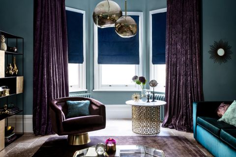 Living room with large bay window, furnished with dark purples and blues