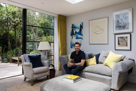George clarke sat in a home with grey sofa, grey armchair and yellow tetbury mustard curtains fitted to door windows