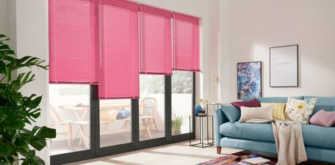 Living room with colourful decor and bifold doors dresed with pink venetian blinds