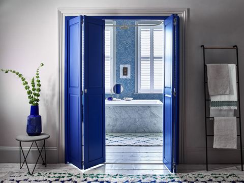 Solid tracked shutters in custom colour blue leading to bathroom