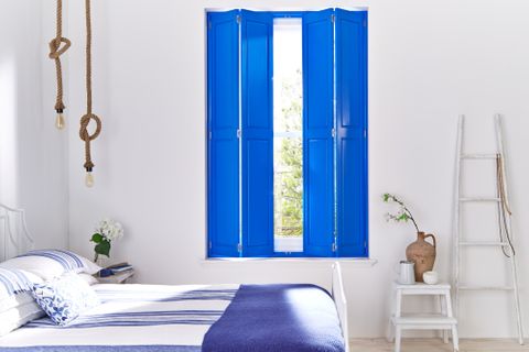 Bright blue solid shutters in bedroom window