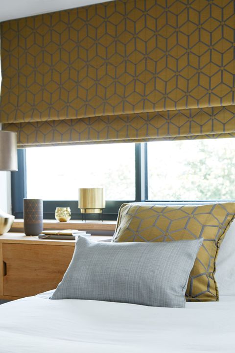 Nexus Brushed Gold Romans blind above a bed