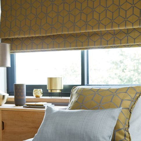 Nexus Brushed Gold Romans blind above a bed
