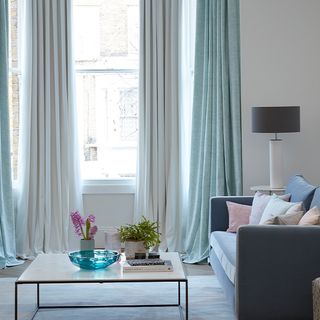 Pastel mint green and white curtains hanging in a modern living room 