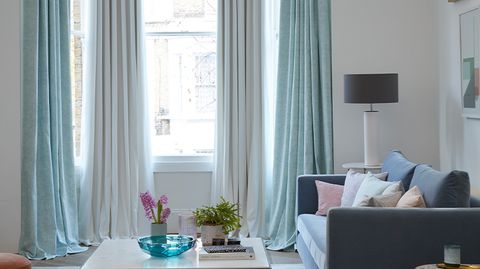 Pastel mint green and white curtains hanging in a modern living room 