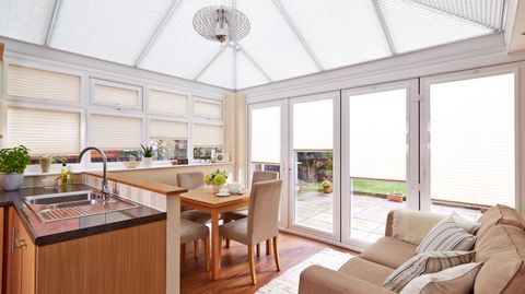 Bright open plan kitchen and dining area with white pleated conservatory blinds