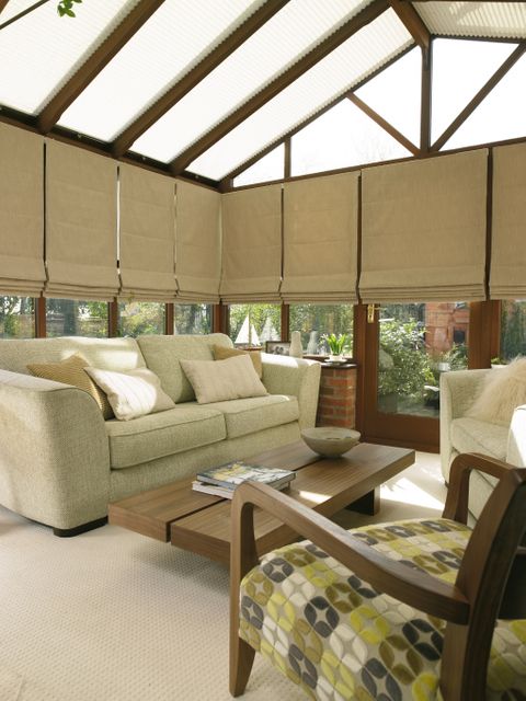 warm and cosy living area in a conservatory with cream sofas and white pleated Conservatory roof blinds