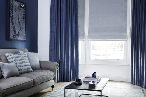 Living room with dark blue curtains layered over pale blue Roman blind