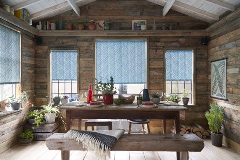 Garden shed used as dining room with teal chevron Roller blinds at the windows