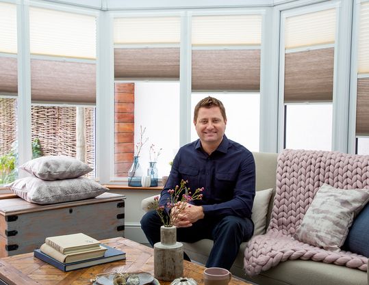George Clarke sitting in a conservatory fitted with Thermashade TM blinds