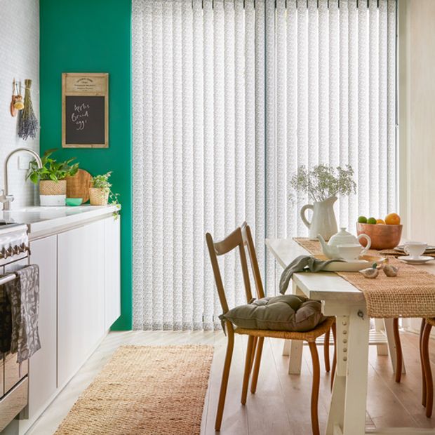 Modern kitchen diner with statement green walls and full length window with patterned vertical blinds
