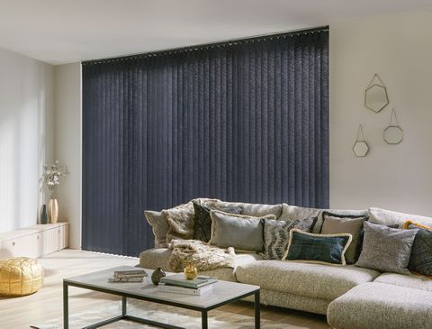 Modern luxe living room with plush cushions with gold accents and charcoal black vertical blinds